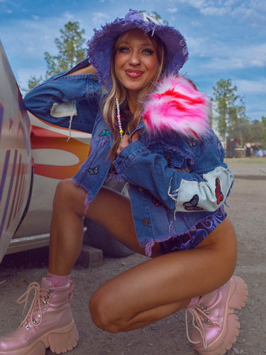 Model Smiling wearing Purple Denim Cropped Jacket with Rainbow Colorful Butterfly Patches and Oversized 70's Style Confetti Pink Faux Fur Collar | LIB Festival Girly Rave Retro Style One of a Kind Fashion | Neon Nomade by Alyssa Risley with Custom Design Jackets, Coats, Outerwear, Headwear, Hats, Water Bottles, and Accessories